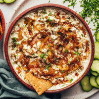Cracker in a bowl of creamy vegan caramelized onion dip
