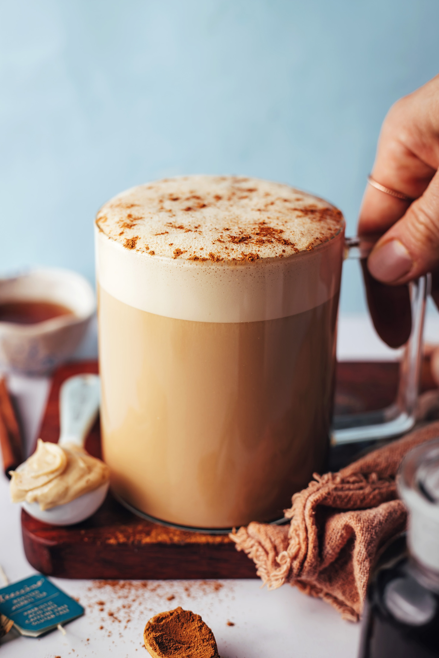 Karahindiba çaylı latte tarifimizin bir kupasını tutan el