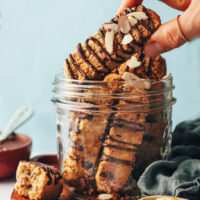 Holding a chocolate chip almond biscotti over a jar
