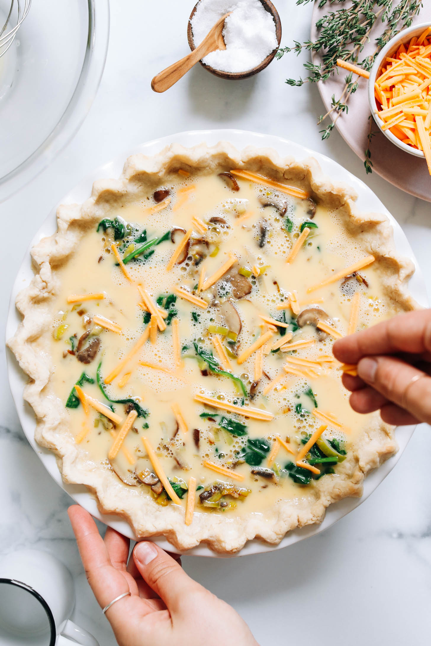 Sprinkling shredded dairy-free cheese over a quiche