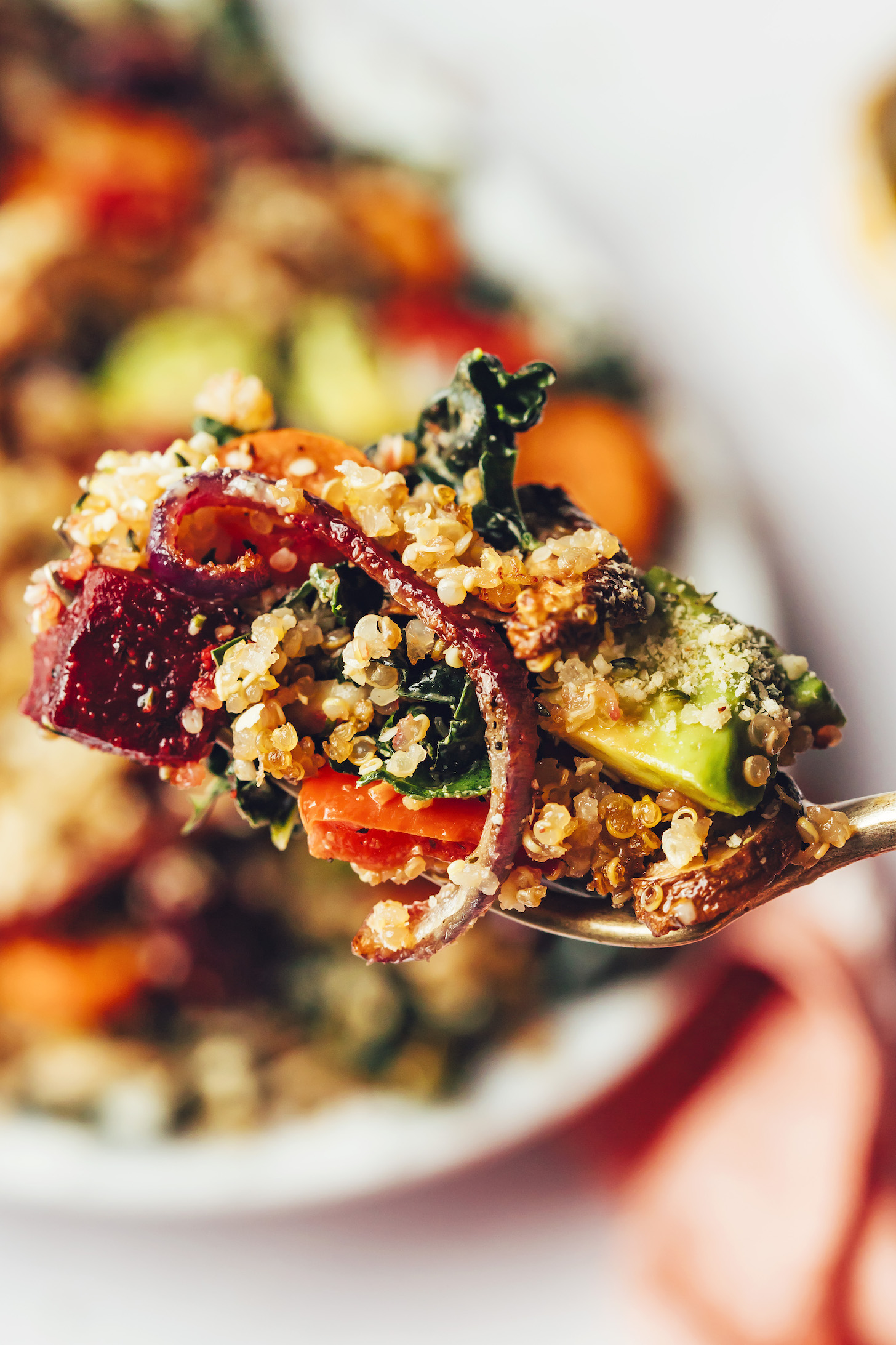 Close-up shot of a fork holding a bite of crispy quinoa and roasted vegetable kale salad