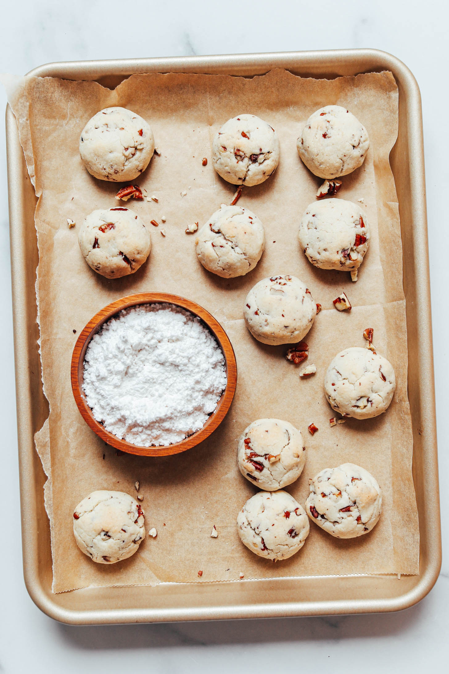 Bol de sucre en poudre et de biscuits aux pacanes fraîchement cuits sur une plaque à pâtisserie