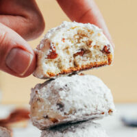Placing a crispy, buttery, pecan-filled Mexican wedding cookie on a stack of cookies