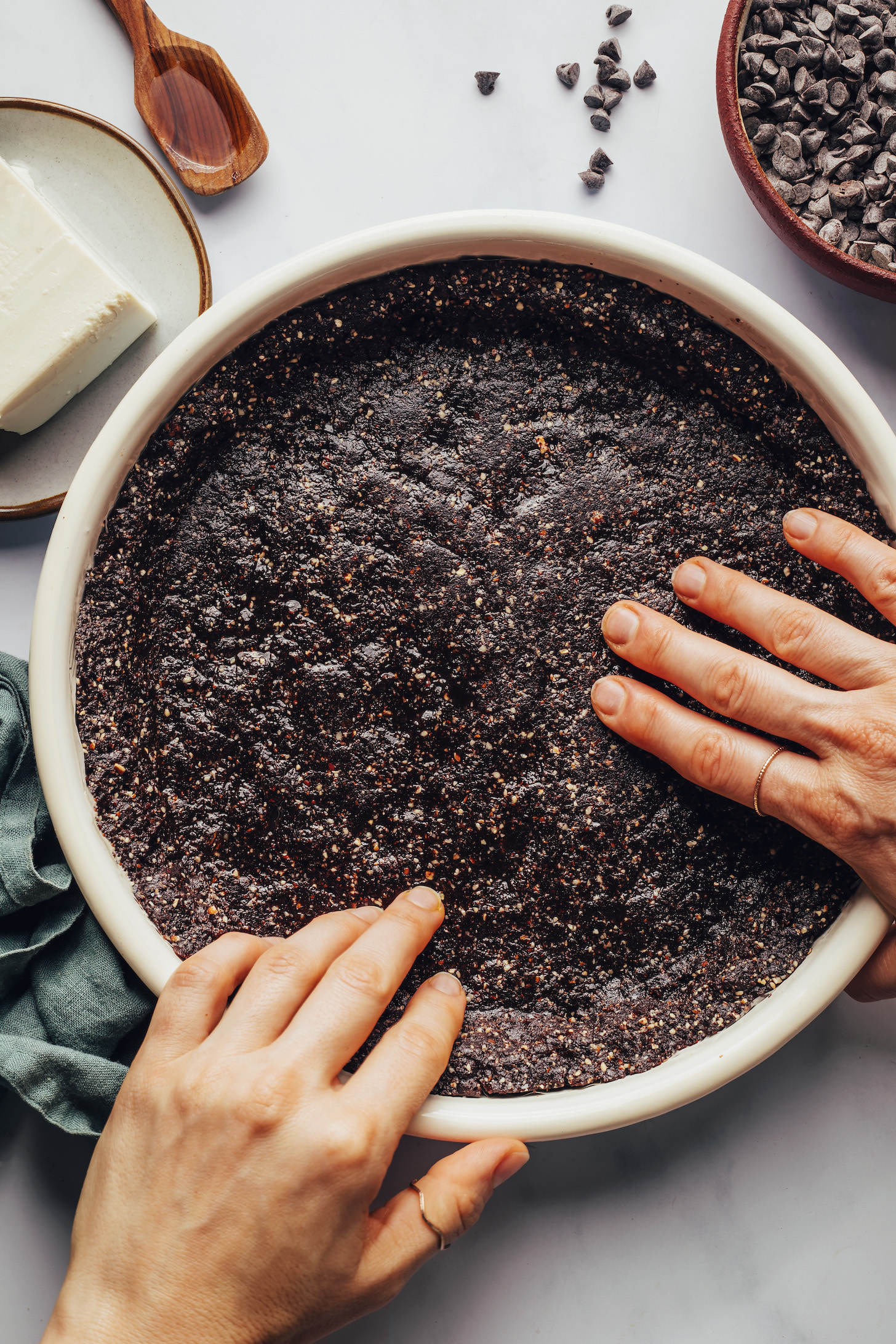 Presionar una corteza de chocolate, dátiles y nuez en un molde para pastel