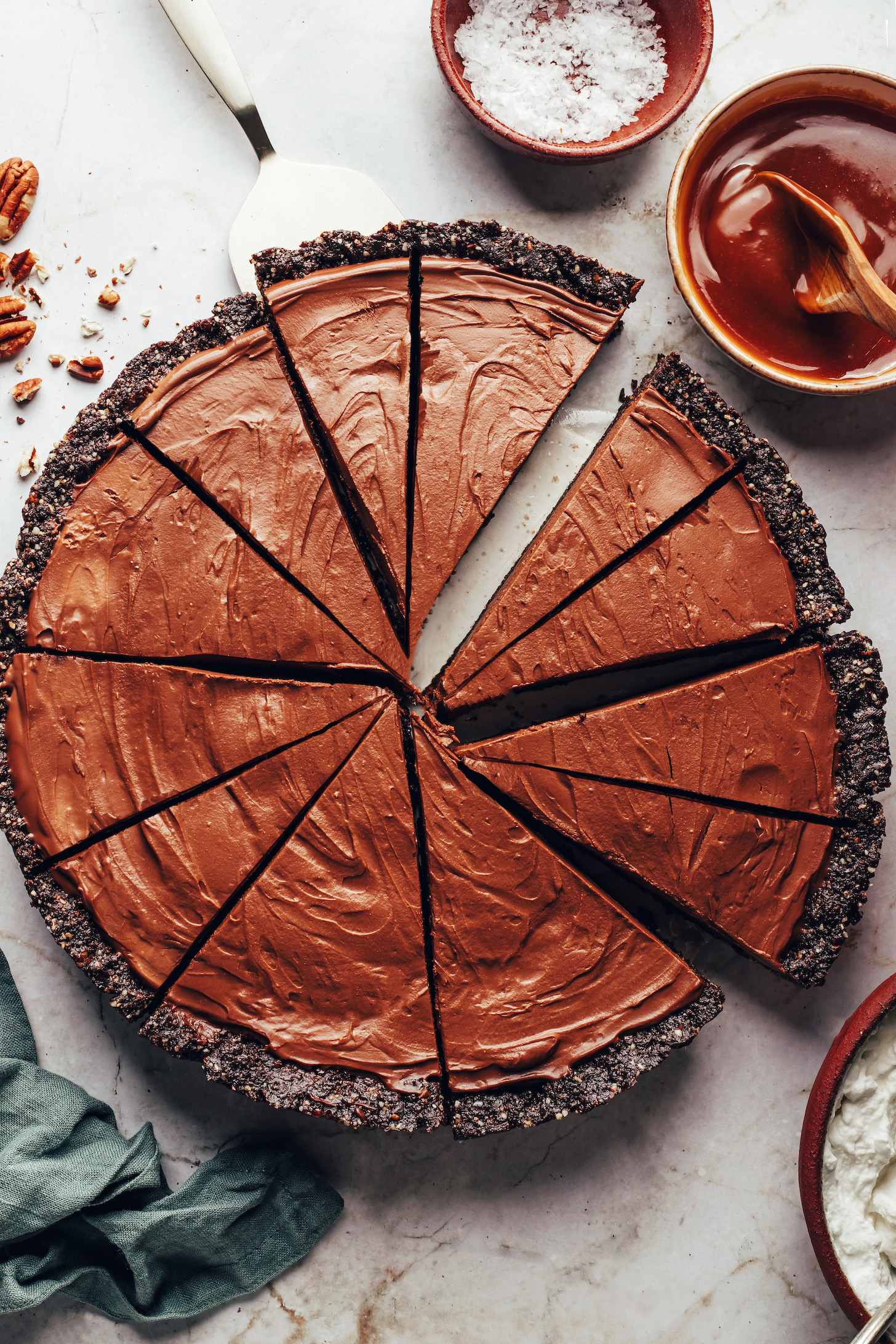 Scheiben unserer doppelten Schokoladenmousse-Torte ohne Backen, umgeben von Zutaten für den Belag