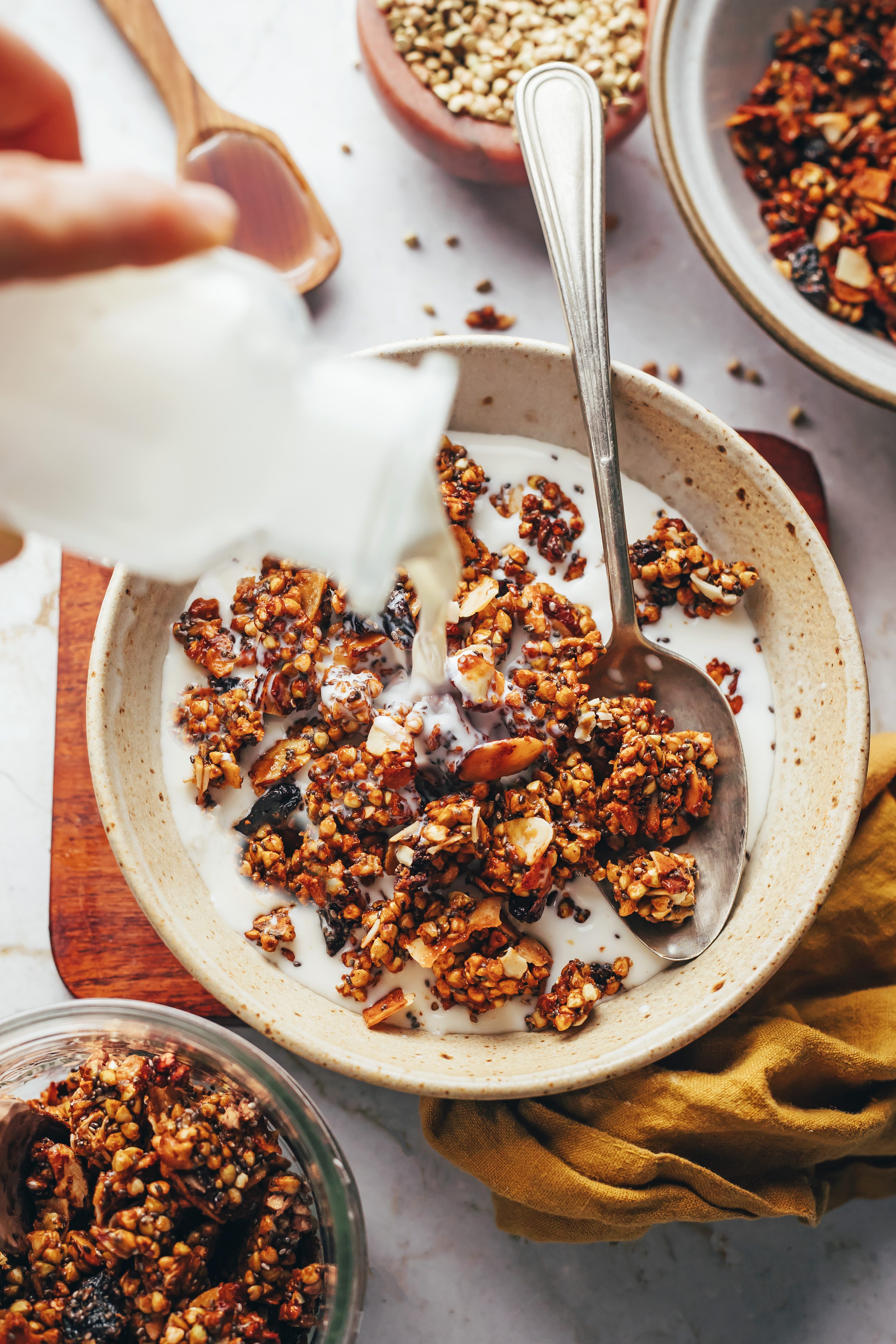 Pouring dairy-free milk into a bowl of oat-free buckwheat granola