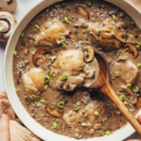 Skillet of cooked chicken thighs in a savory mushroom coconut milk sauce