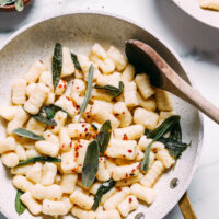 Skillet of gluten-free gnocchi sautéed in vegan butter with crispy sage and red pepper flakes