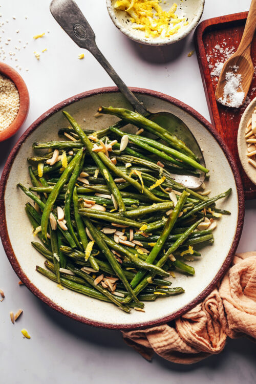 Overhead shot of a bowl of roasted green beans with lemon zest and almonds