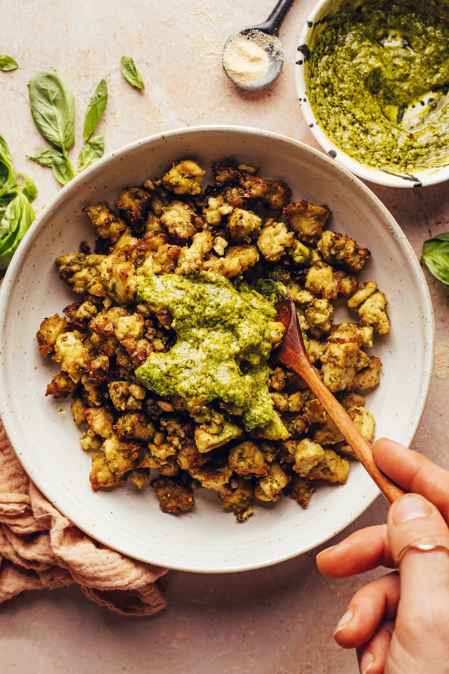 Mixing crispy baked tofu and pesto in a bowl