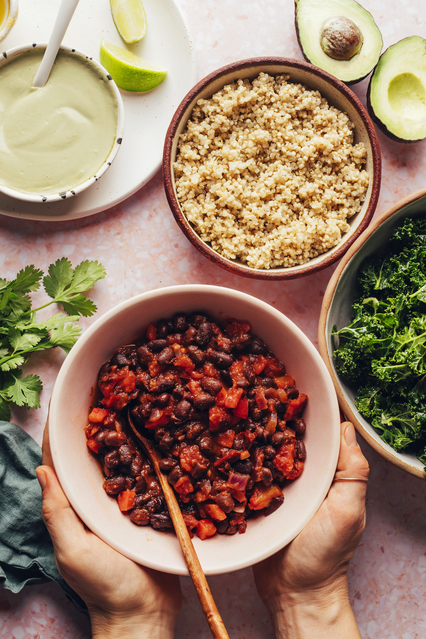 Hands around a bowl of chili next to other ingredients to make vegan chili bowls