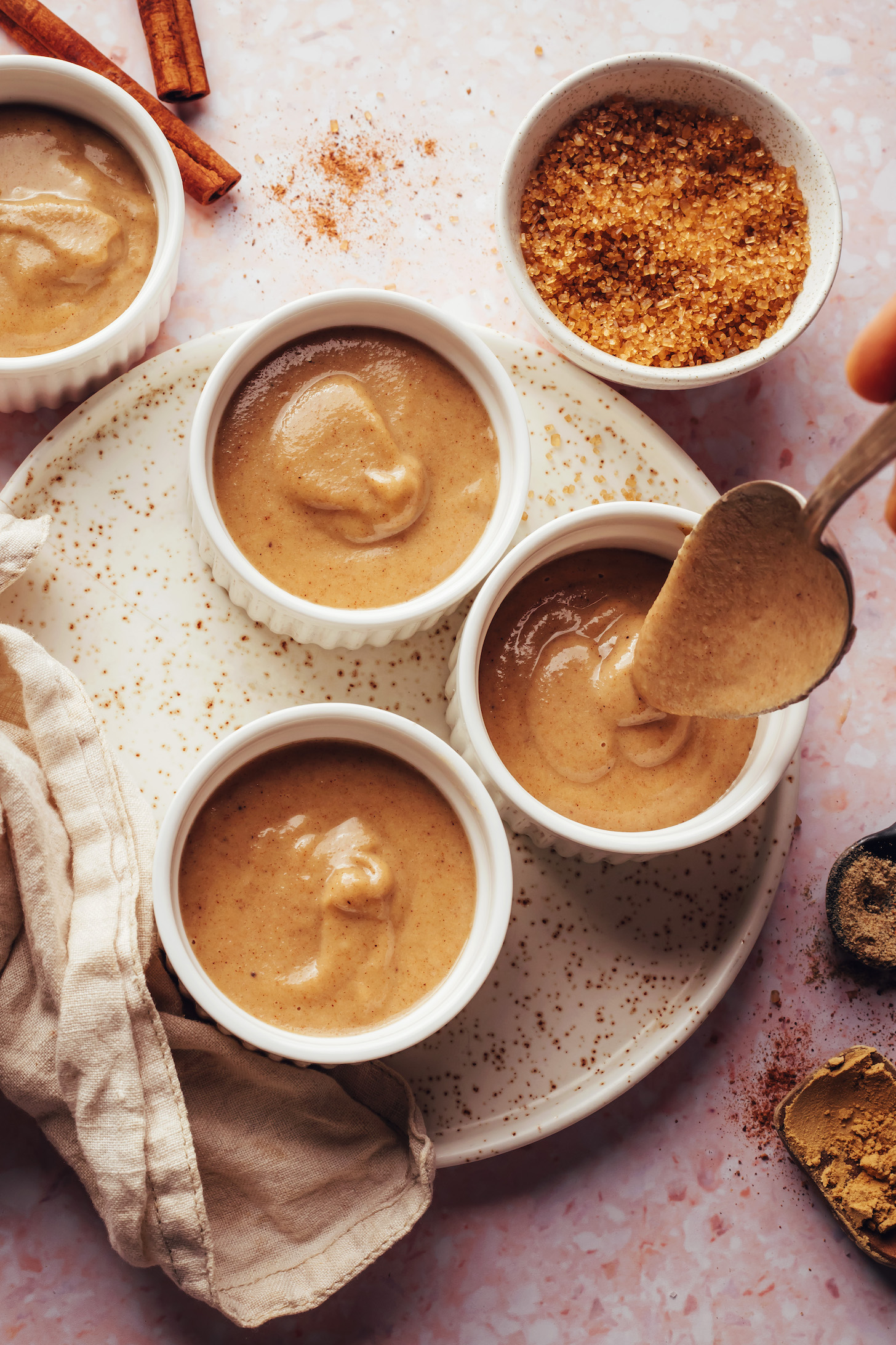 Use a spoon to transfer a creamy vegan tea-spiced custard into ramekins