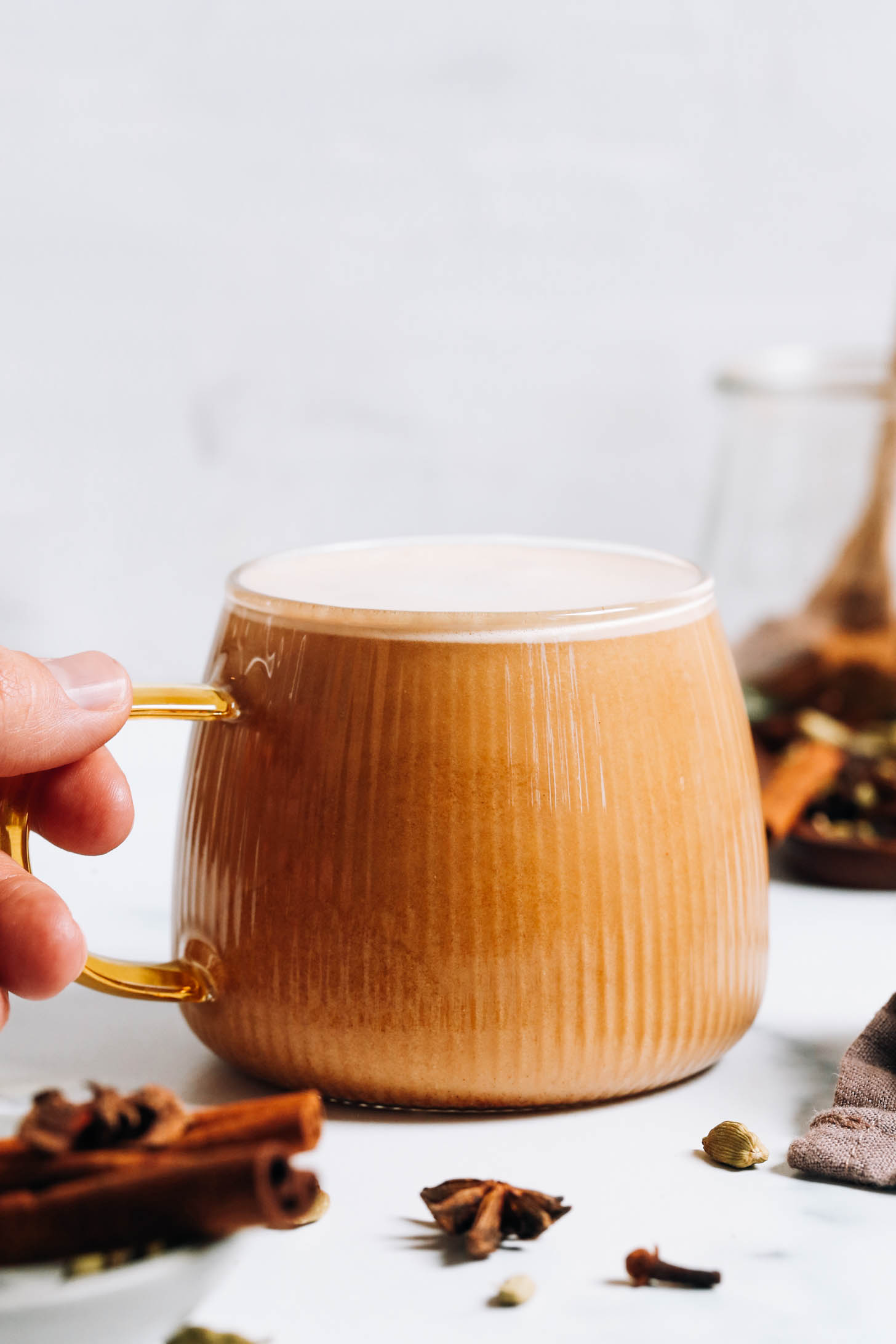 Sosteniendo el asa de una taza de chai latte sucio vegano