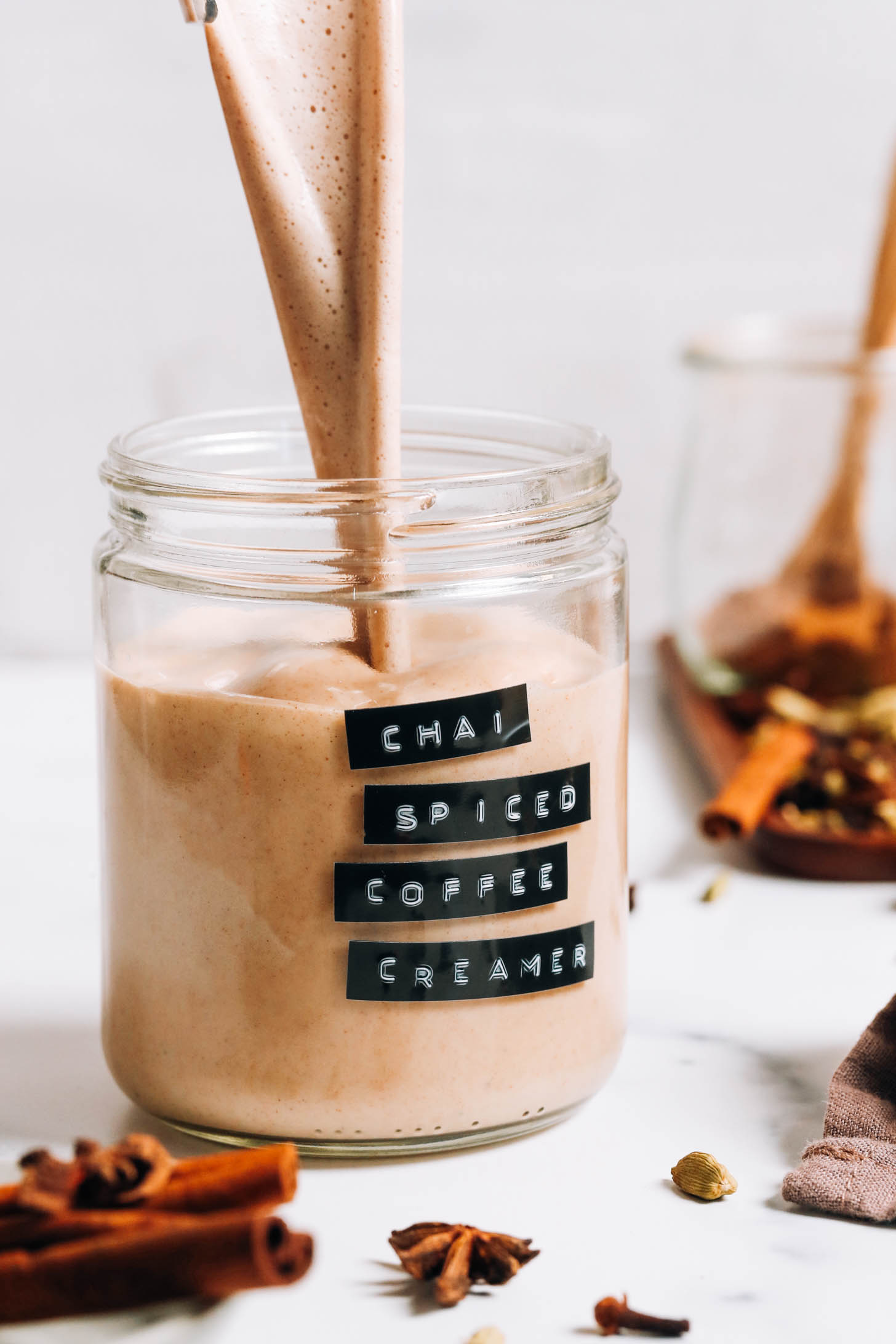 Pouring a creamy chai-spiced coffee creamer into a jar