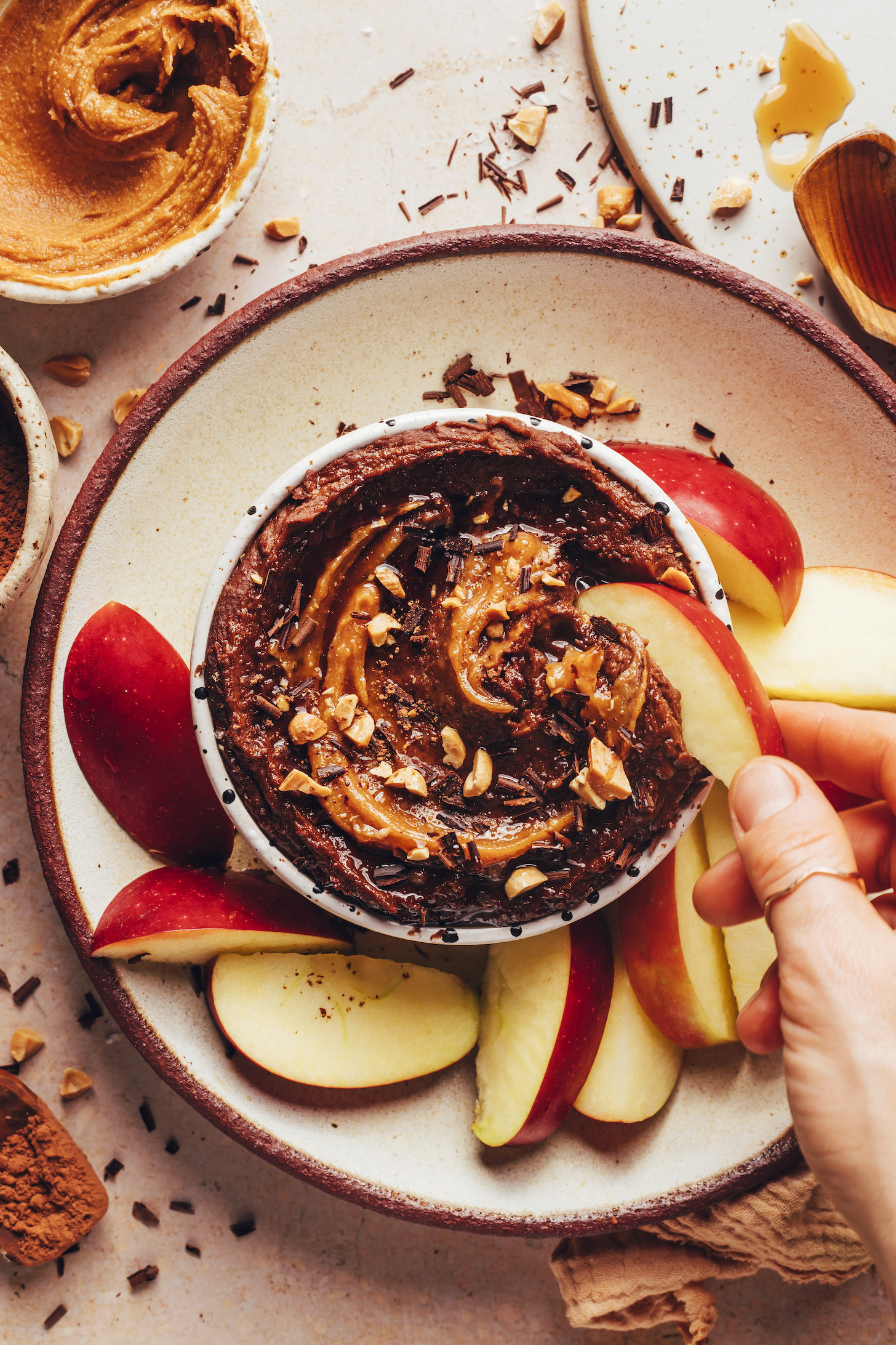 Dipping an apple slice into a bowl of chocolate peanut butter hummus