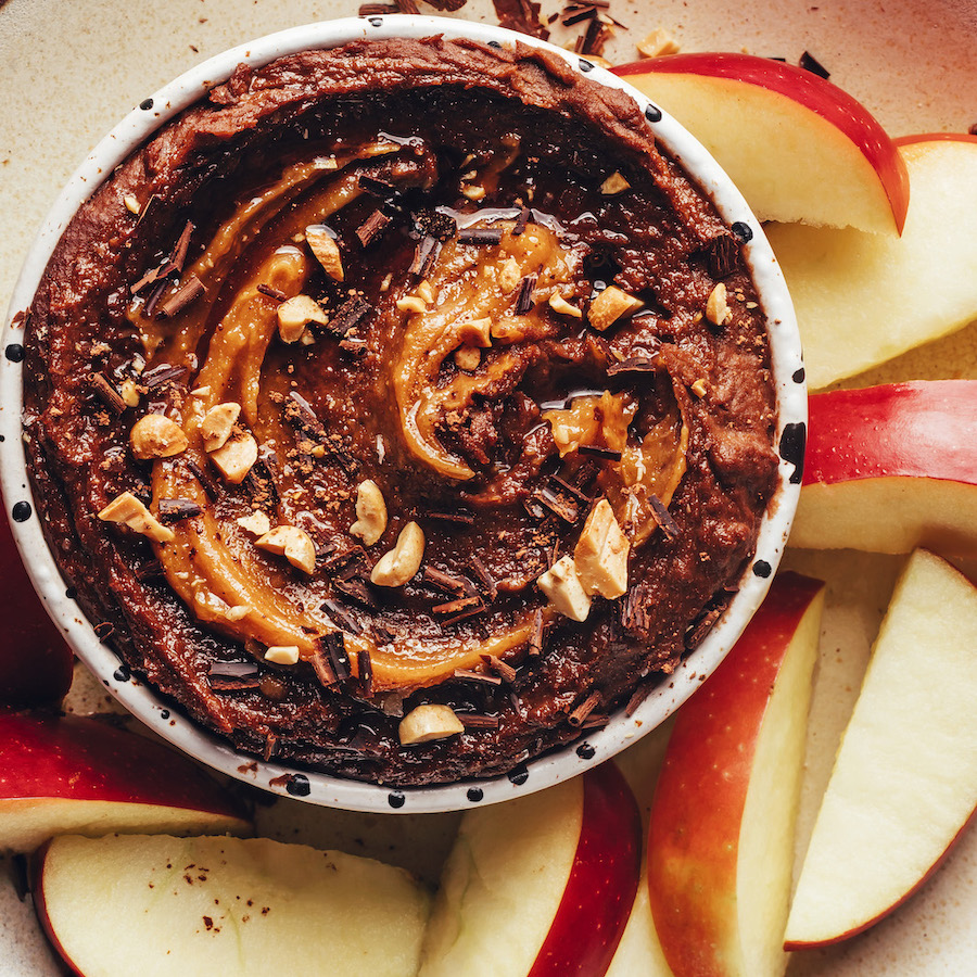 Overhead shot of sliced apples around a bowl of chocolate peanut butter dip