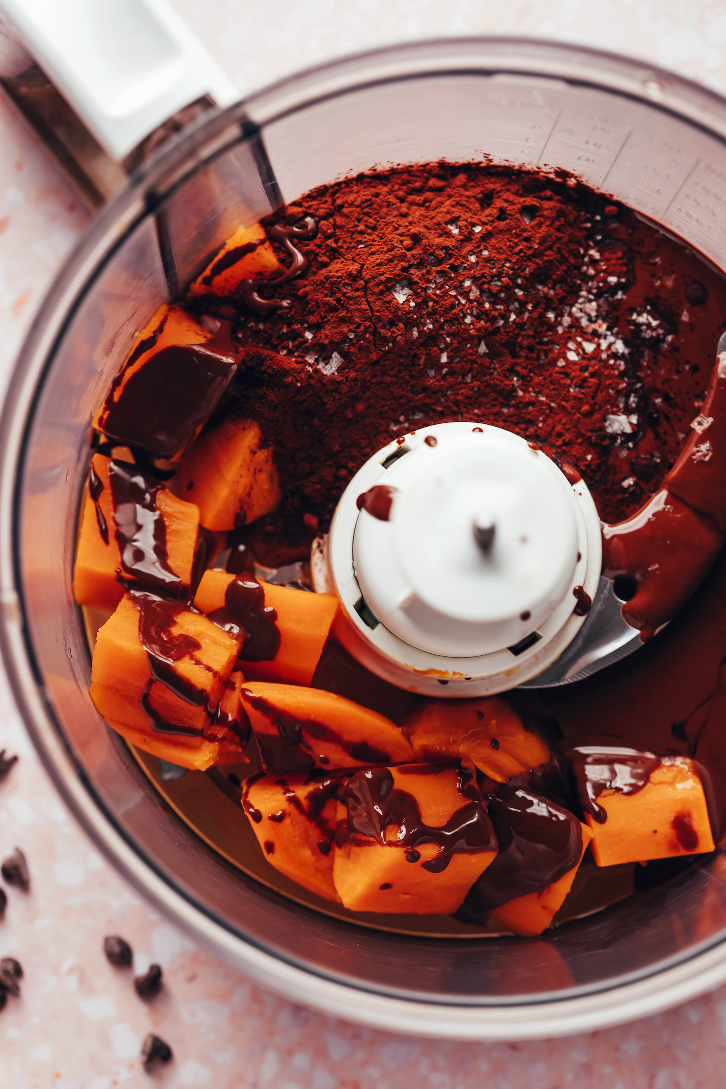 Food processor with steamed sweet potatoes, melted dark chocolate, salt and cocoa powder