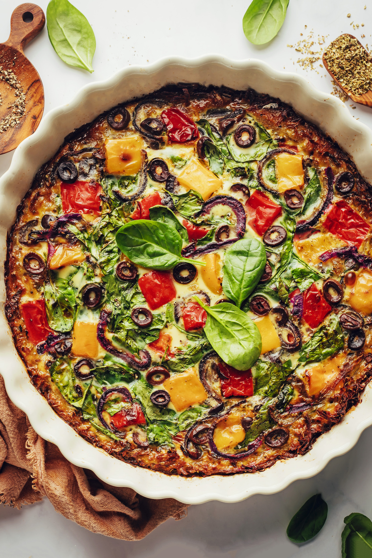Mediterranean quiche with bell peppers, onion, spinach, olives, and a potato crust