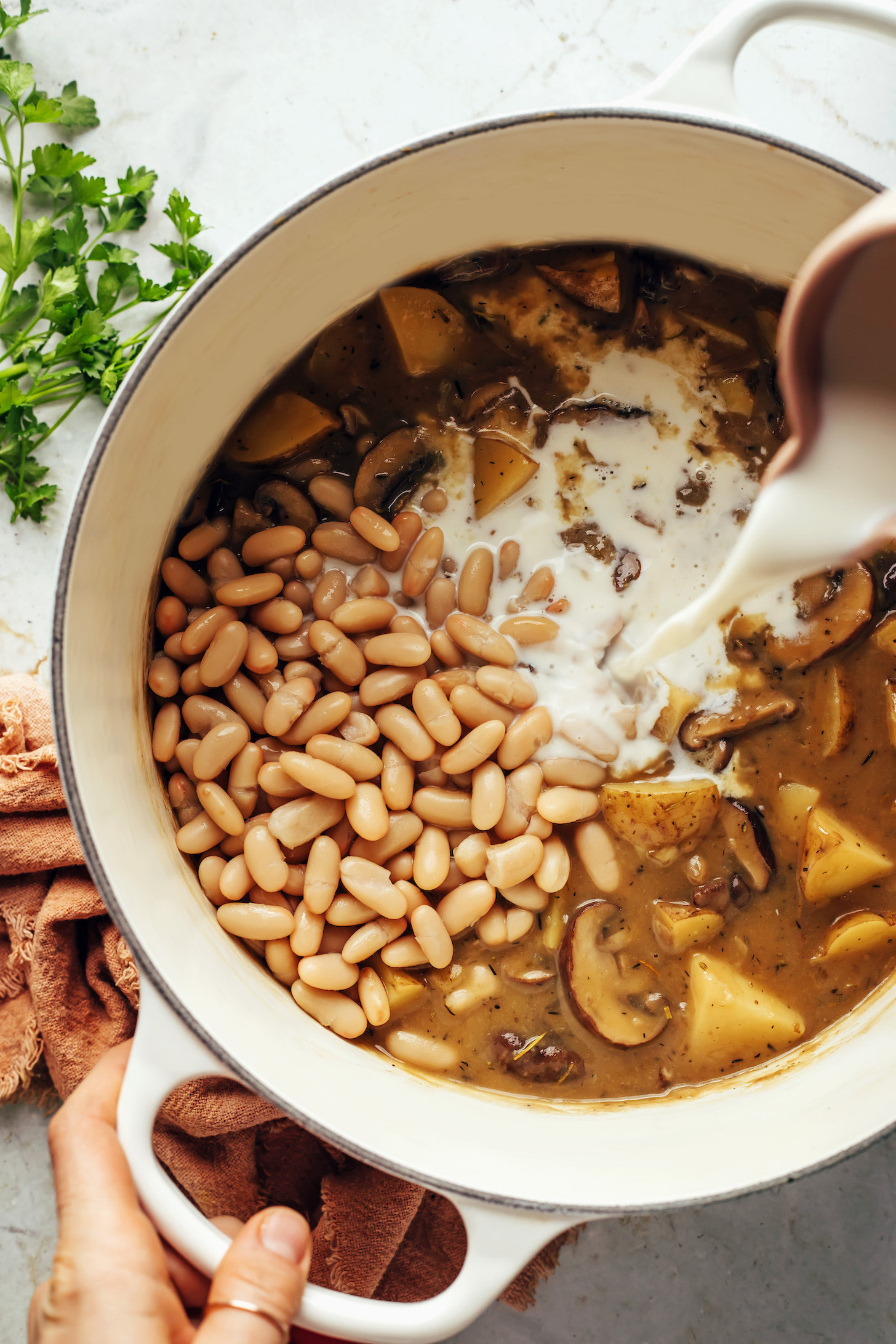 Pour almond milk into a pot of white bean mushroom stew