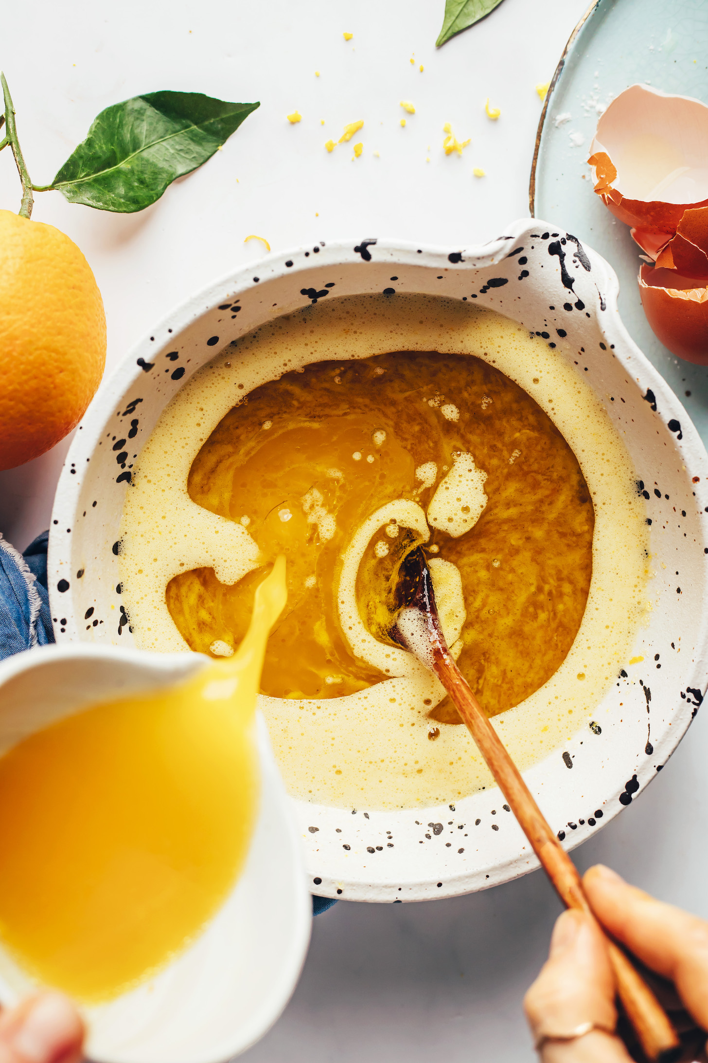 Выливание апельсинового сока в миску с другими влажными ингредиентами