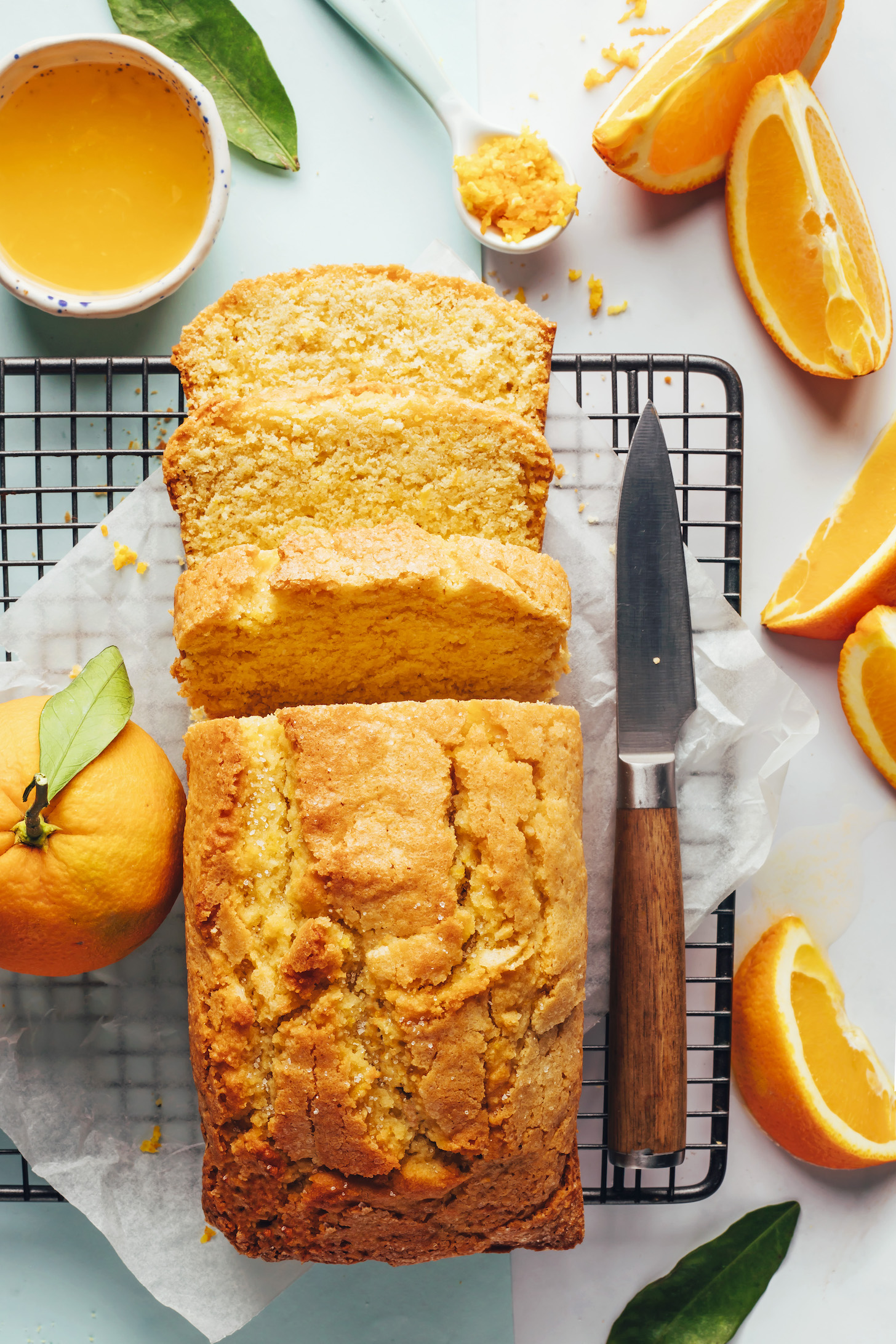Pan parcialmente rebanado de pastel de naranja y almendras en una rejilla para enfriar