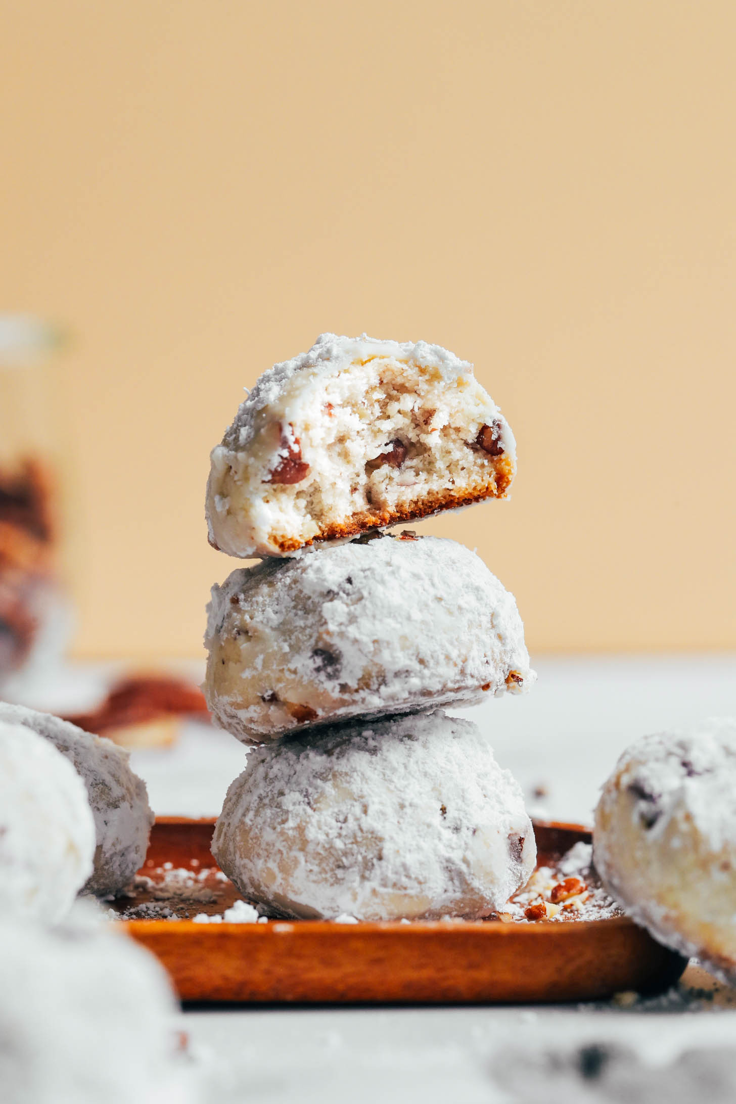 Stack of vegan gluten-free Mexican wedding cookies with the top one partially eaten