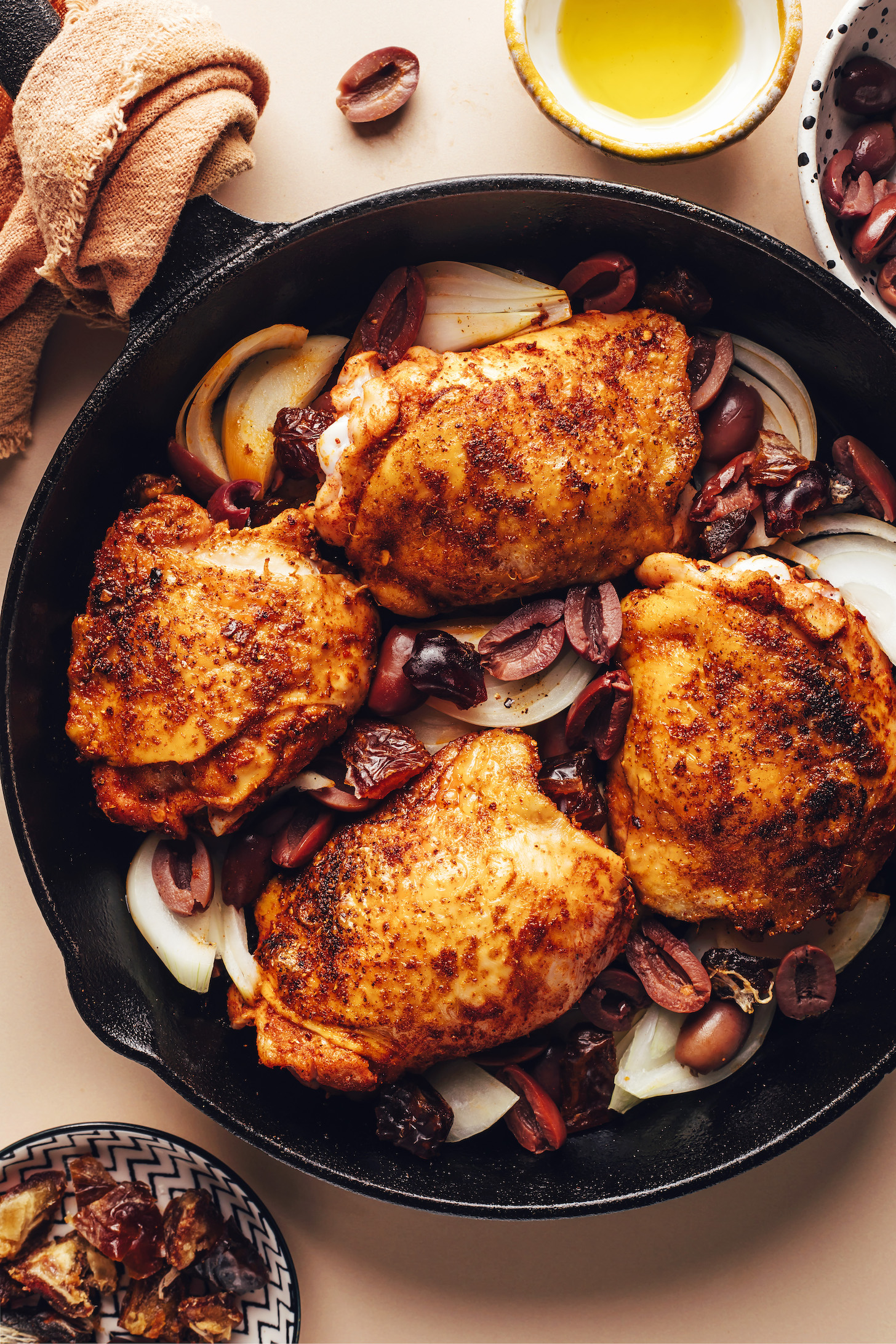 Kalamata olives and onions surrounding crispy pan seared chicken thighs in a cast iron skillet