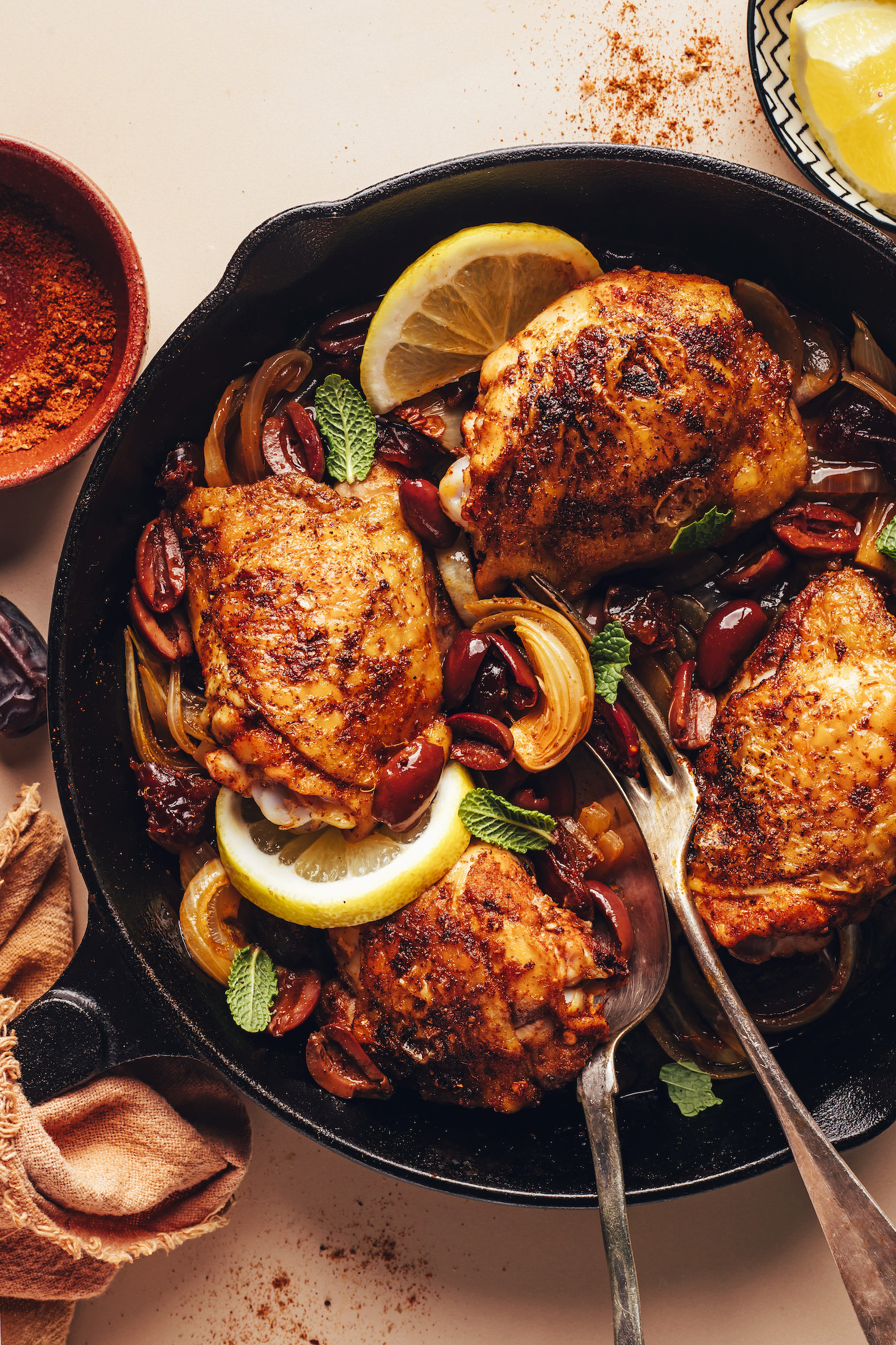 Pan of crispy baked chicken thighs surrounded by olives and caramelized onions
