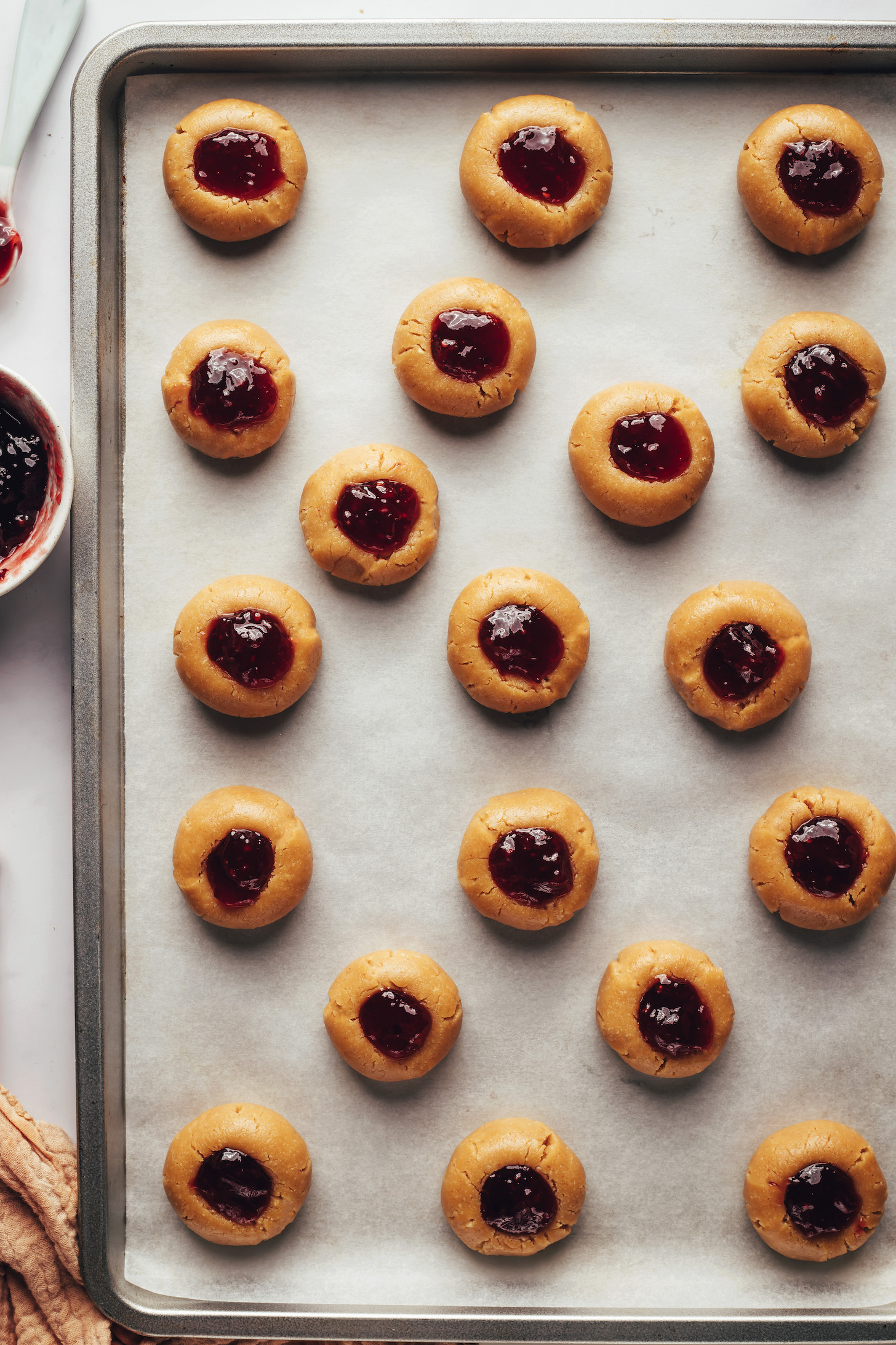 Dollops of jam inside peanut butter dough with the centers pressed in