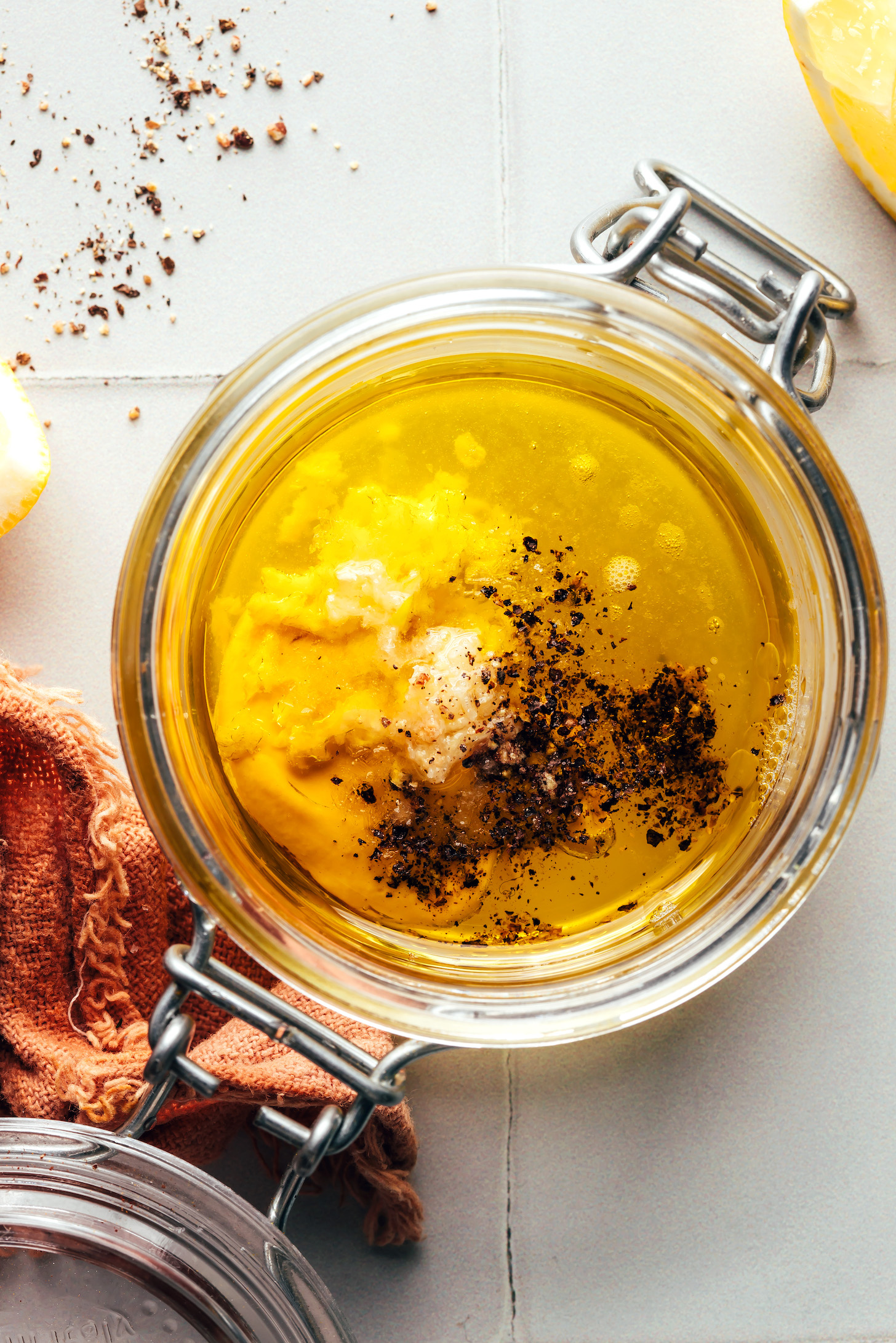 Overhead shot of a jar with olive oil, lemon juice, garlic, Dijon mustard, salt, and pepper