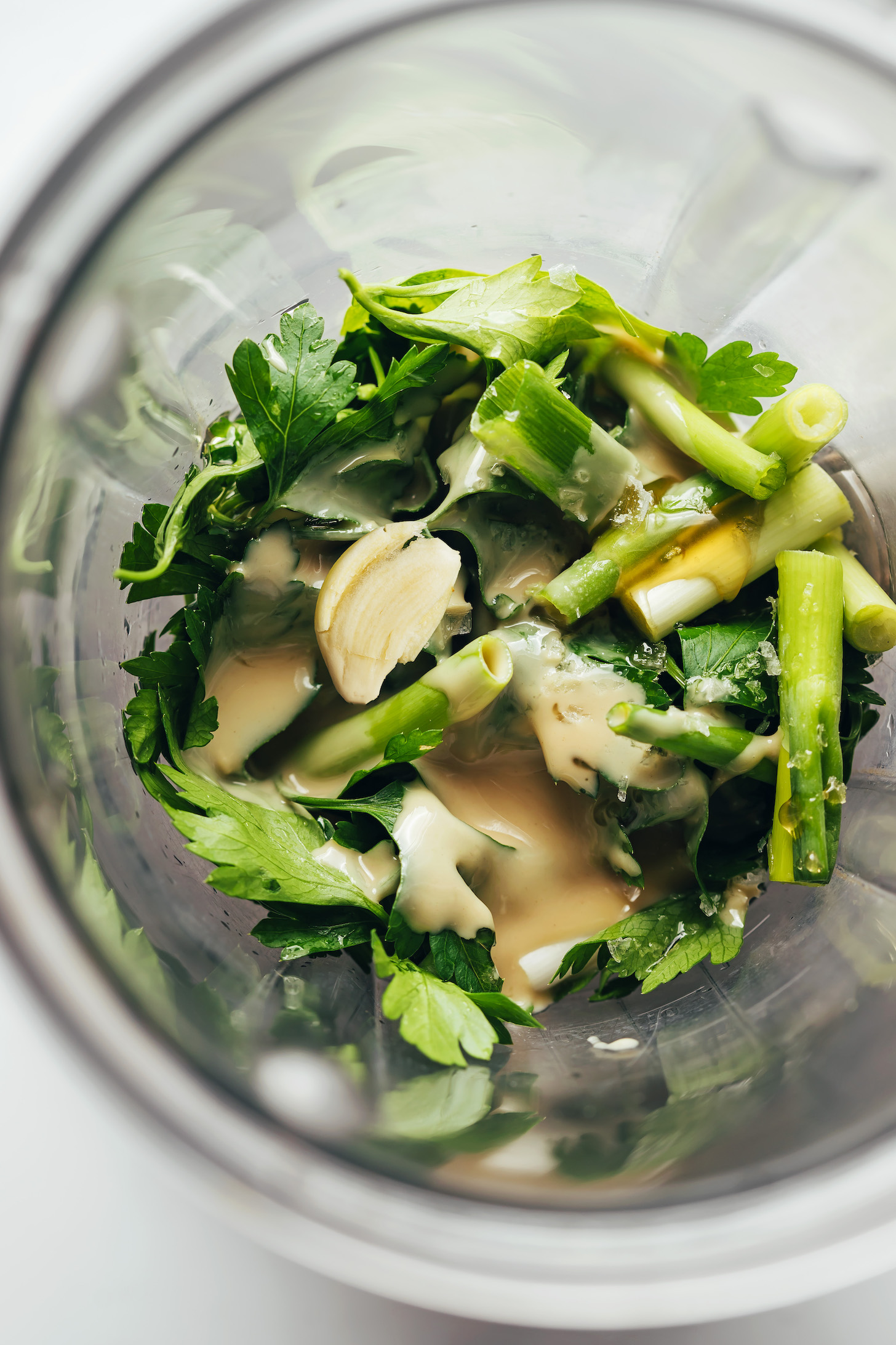 Blender with tahini, green onion, garlic, salt, maple syrup, and other ingredients