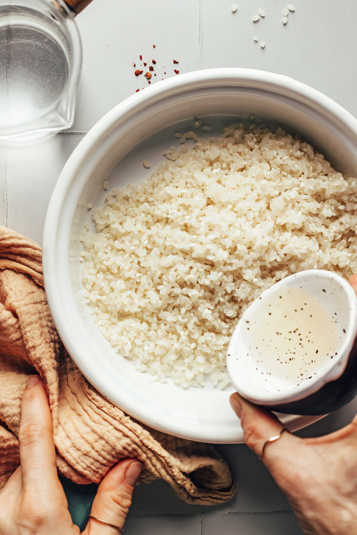 Выливание рисового уксуса в кастрюлю с рисом для суши