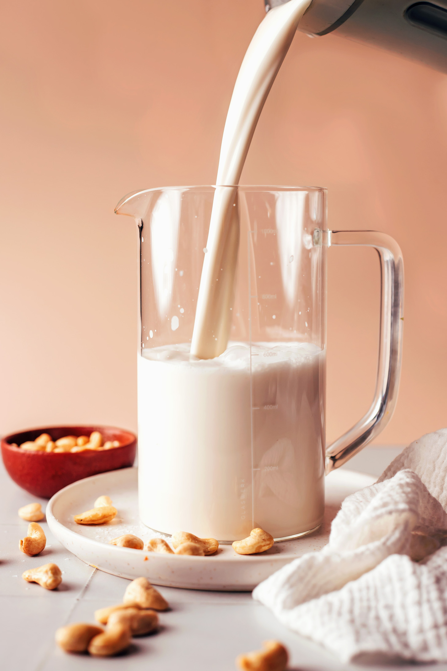 Pouring cashew milk from a blender into a pitcher for our tutorial on how to make cashew milk