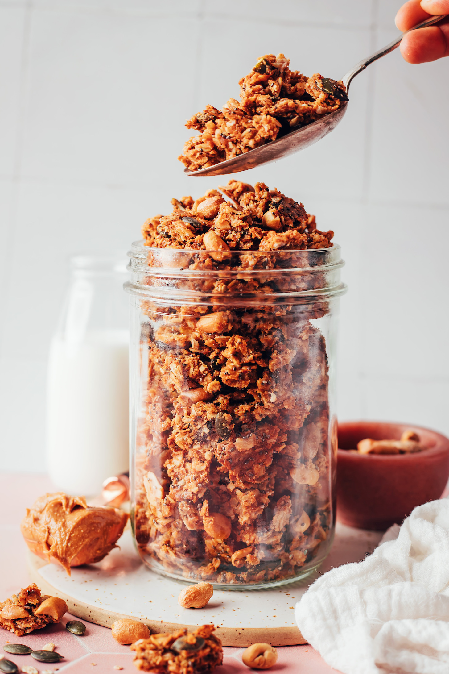 Holding a spoonful of peanut butter cookie granola over a jar