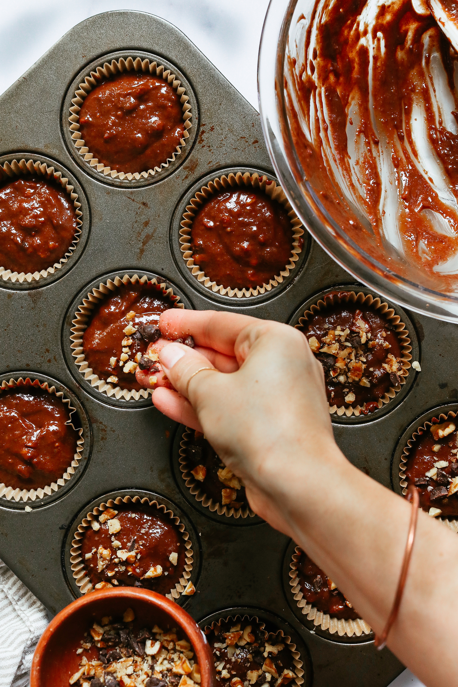 Посыпать измельченными грецкими орехами и шоколадной стружкой тесто в форме для маффинов.
