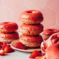 Stack of glazed strawberry donuts on a plate