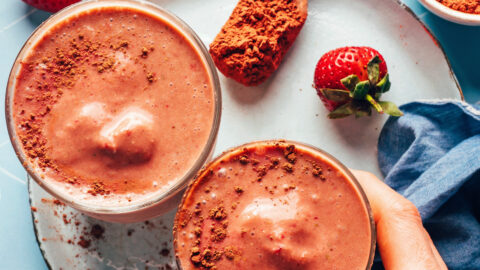 Hand reaching in to pick up a glass of our creamy vegan chocolate breakfast shake recipe