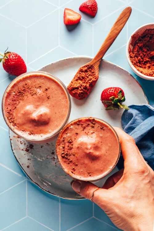 Hand reaching in to pick up a glass of our creamy vegan chocolate breakfast shake recipe