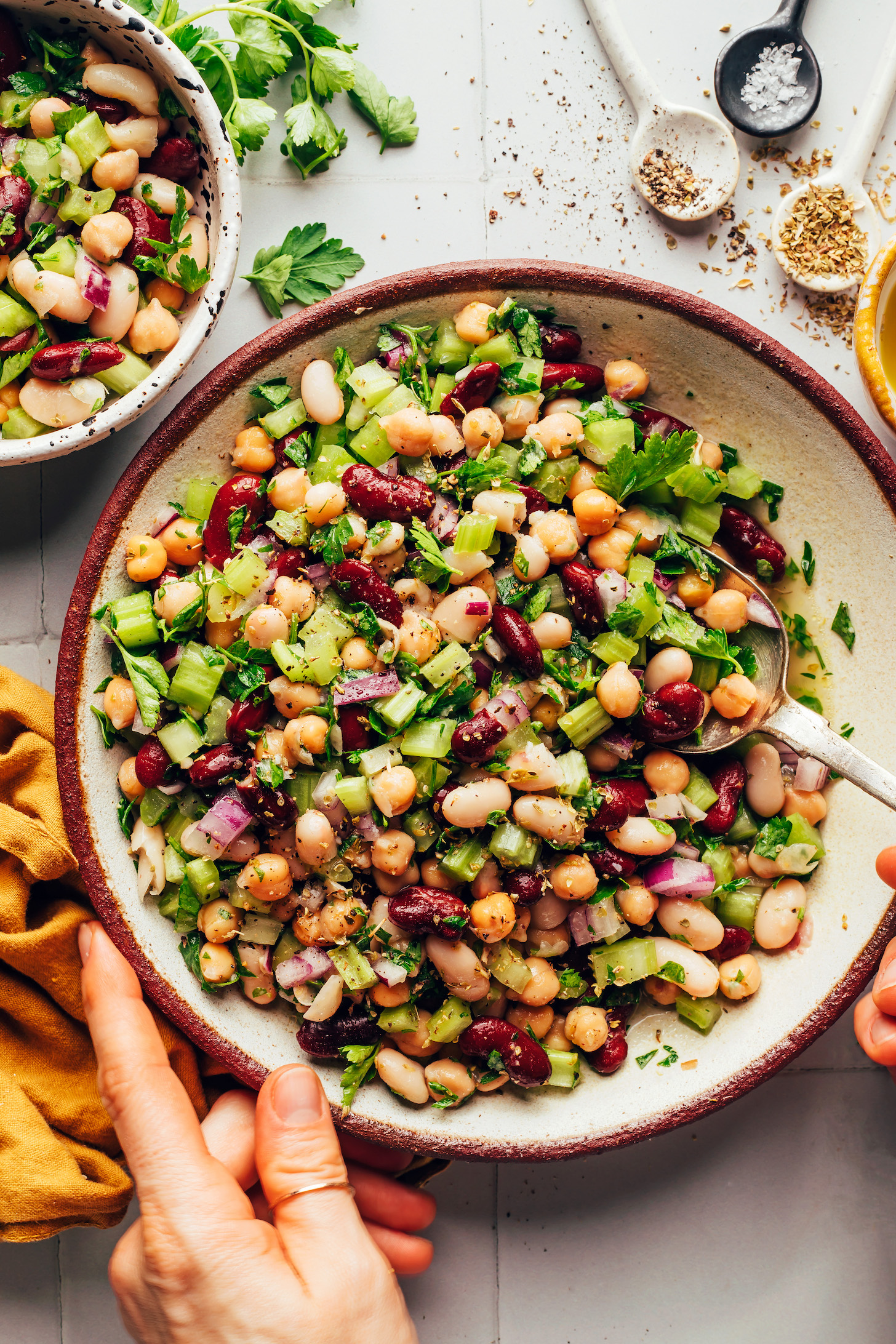 Hands holding a spoon and the side of a bowl of our easy three bean salad recipe