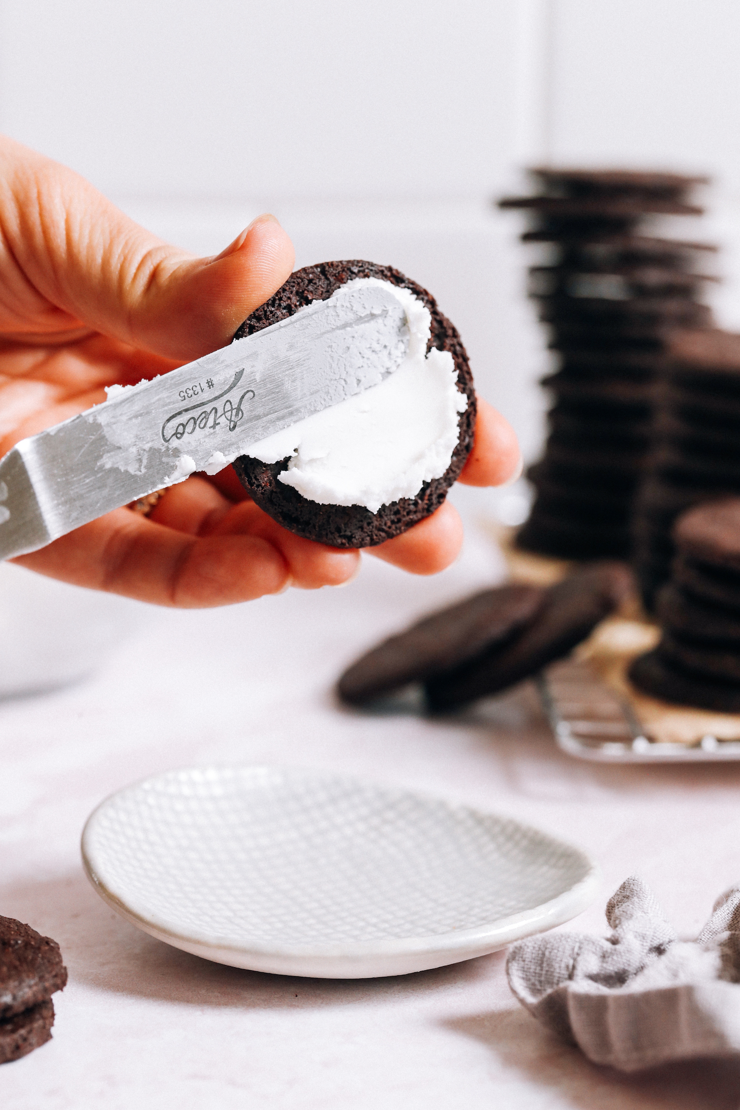 Spreading homemade Oreo filling onto a chocolate cookie
