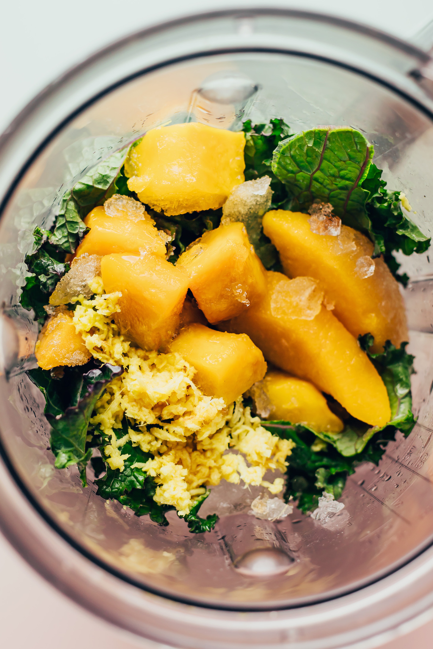 Blender with mango, peach, ginger, kale, and ice