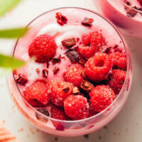 Overhead shot of a raspberry banana smoothie with cacao nibs and fresh raspberries