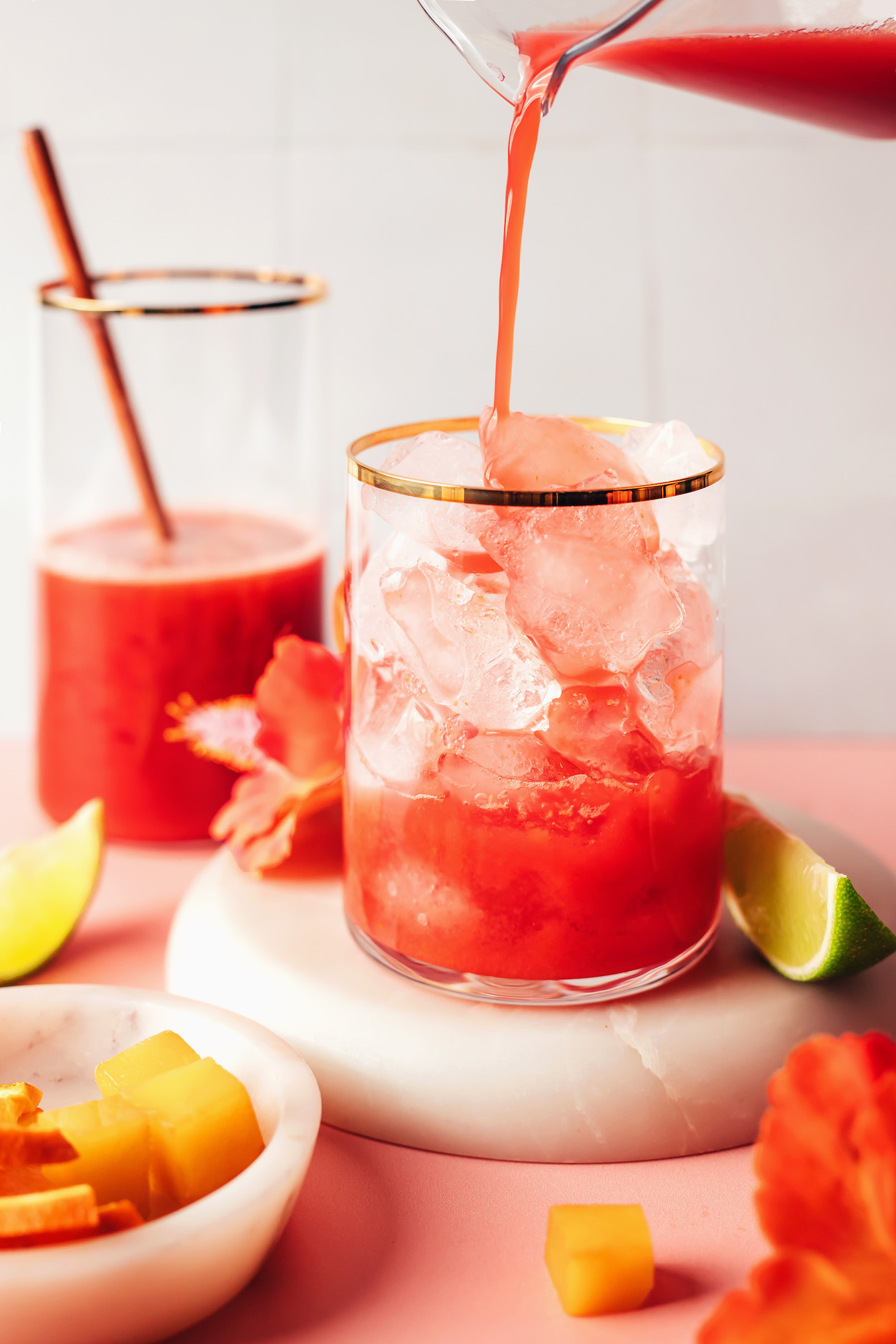 Verter una mezcla de hibisco, naranja y mango sobre hielo en un vaso