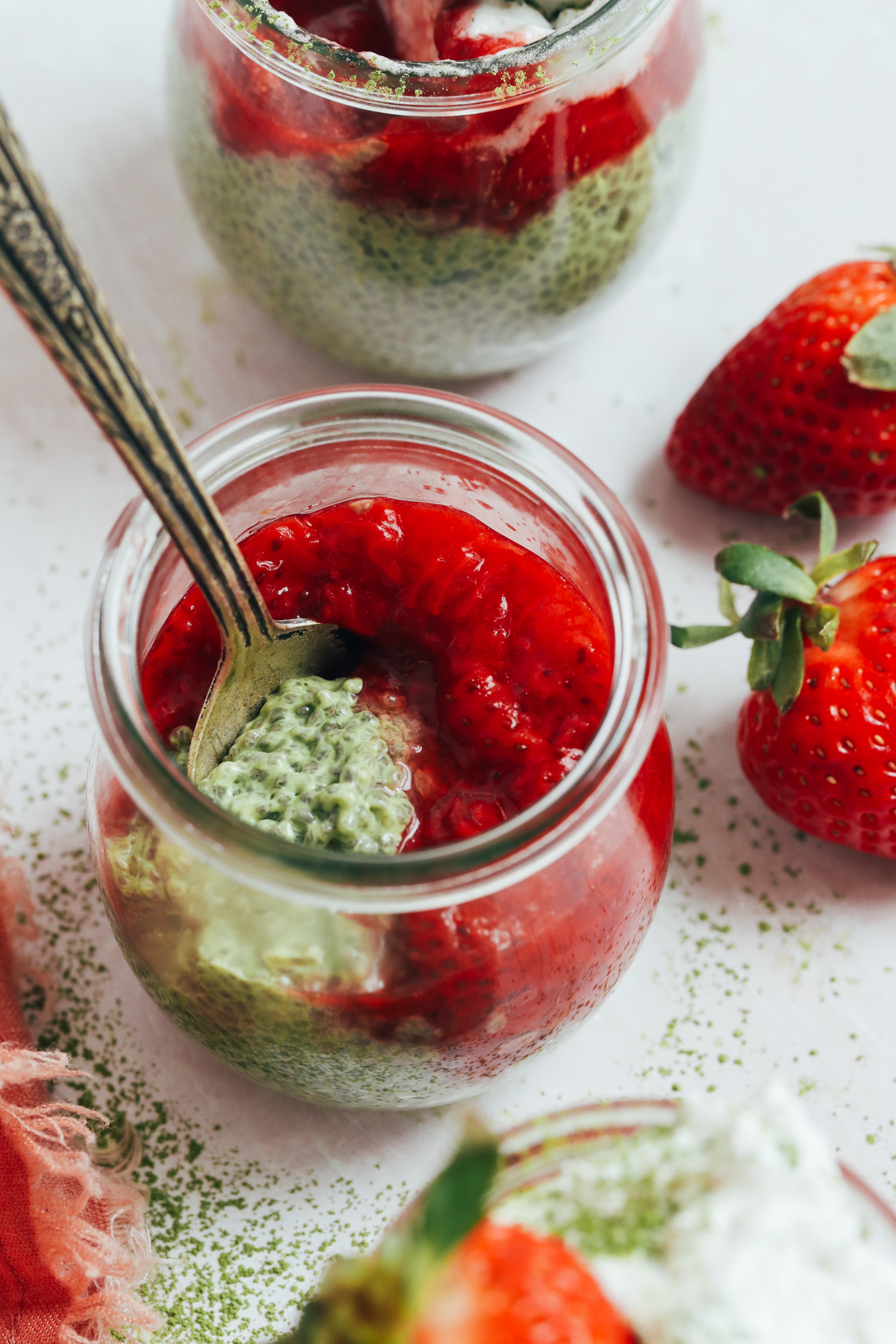 Overhead shot of a jar of matcha chia pudding topped with strawberry compote