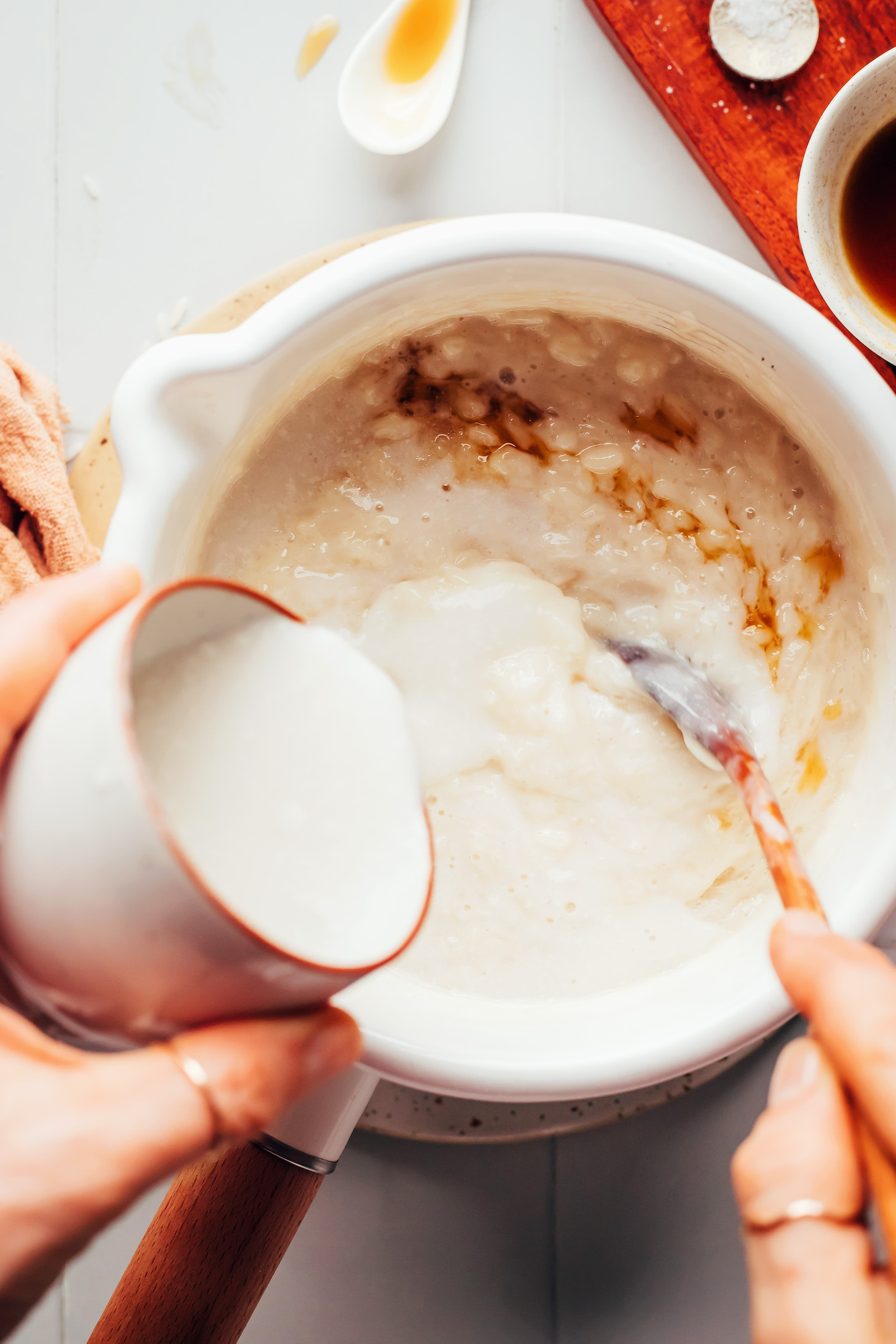 Verter leche de coco en una olla con jarabe de arce, vainilla, leche de almendras y arroz blanco cocido