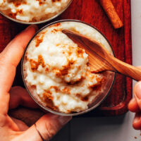 Using a wood spoon to scoop up a bite of creamy vegan rice pudding