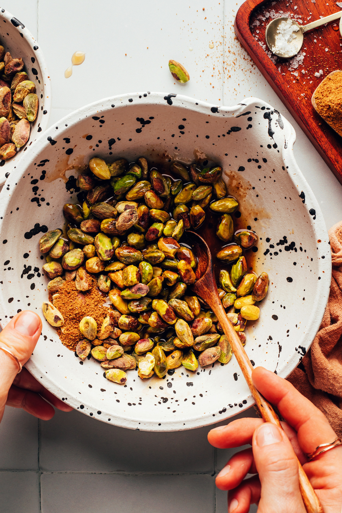 Stirring together pistachios with maple syrup and coconut sugar