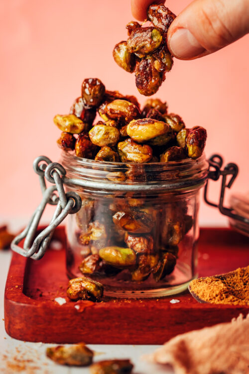 Holding a cluster of candied pistachios over a jar with more of them
