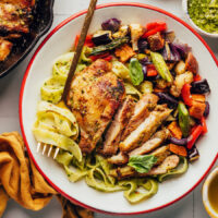 Plate of pasta, pesto chicken thighs, and roasted veggies