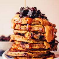 Drizzling maple syrup onto a stack of plantain pancakes